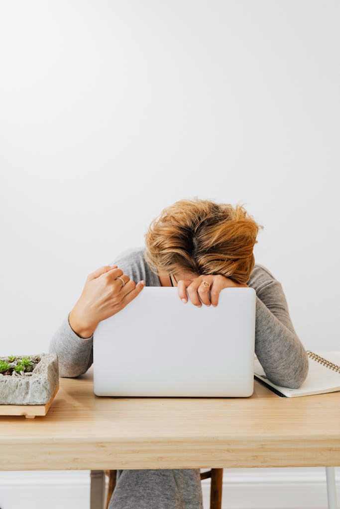 Woman showing fatigue resting head on laptop, workspace stress.